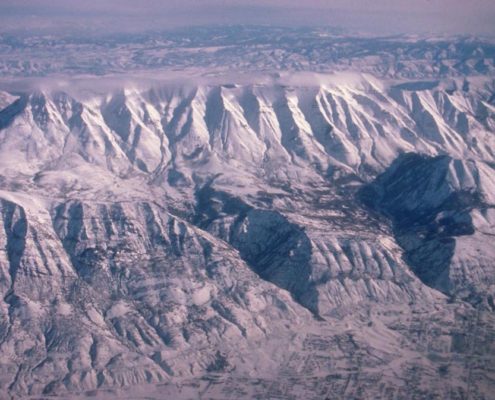 The eastern edge: Mt. Timpanogos, in the Wasatch Range of Utah. Mt. Timpanogos is the second highest peak of the Wasatch Range, at an elevation of 11749&#039;. The Wasatch Range rises along the Wasatch fault, which is an active fault, and so poses a significant earthquake hazard to the Salt Lake City region. As evidence of recent faulting, two wineglass canyons can be seen behind the fault on the right side of the photo. (ID: 477-89)